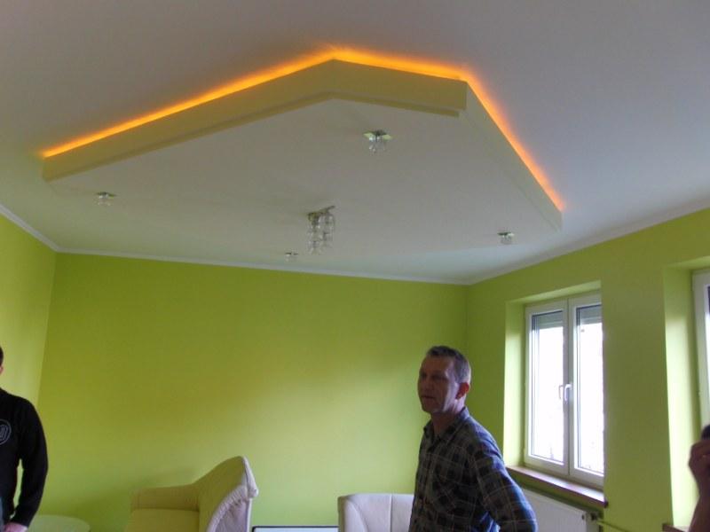 Pomarańczowe oświetlenie LED w suficie podwieszanym w pokoju z limonkowymi ścianami i widocznym fragmentem okna.